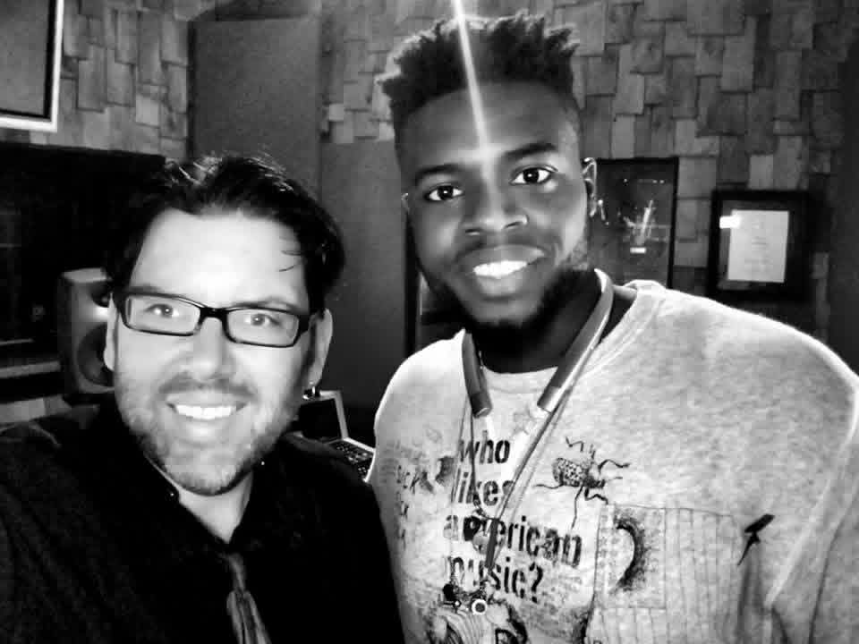 Black-and-white photo of Jack Miele with a collaborator wearing headphones and a beetle sweatshirt in the studio