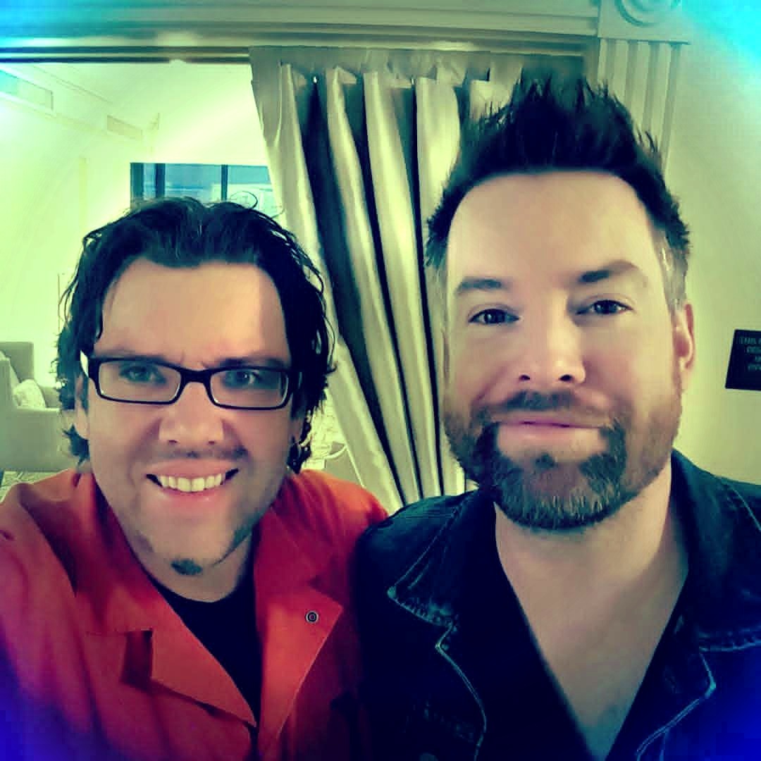 Jack Miele smiling in a backstage selfie with a bearded friend